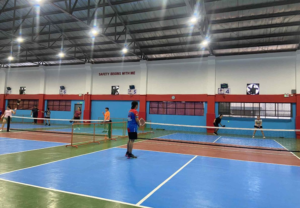 Players in a doubles rally on one of the indoor courts at Crisron Pickleball Courts.